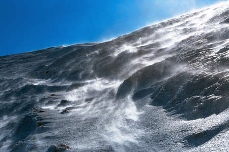Dangerous windy snow blow on ice slope alpine hiking path, Italyの写真素材