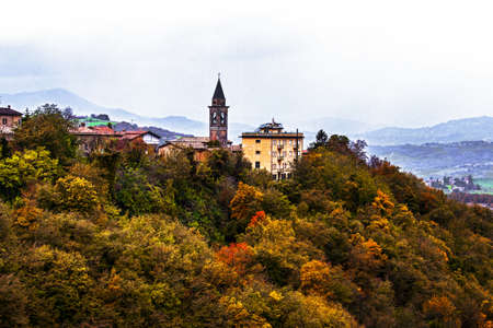 Scenic view of italian countryside medieval village and church against autumn foliage during a cloudy day, Matilde Canossa Trail, Reggio Emilia, Italyの写真素材