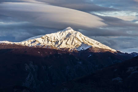 Scenic view of snow capped mountain Succiso Alp during a cloudy sunset, Ventasso, Appennino Tosco Emiliano National Park, Italyの写真素材