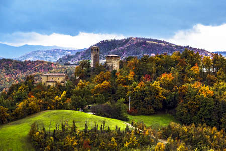 View of italian countryside village against autumn foliage during a cloudy day, Sarzano Castle,...