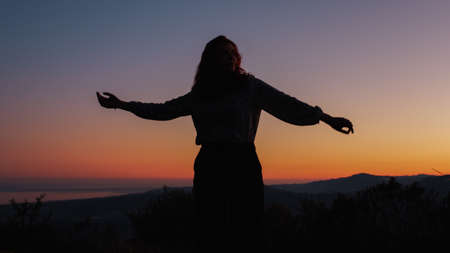 silhouette of carefree dancing girl at sunsetの写真素材