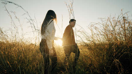 Couple Walks outdoor In A Field At Sunset