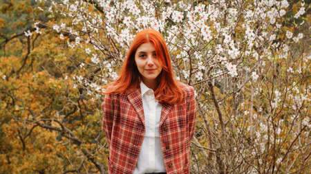 Happy red-haired girl under spring flower tree. Spring mood.