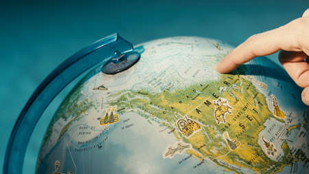 Close up of finger pointing on globe