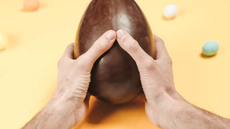 Opening a chocolate easter egg on yellow background