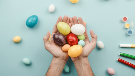 hand with colorful easter eggs on blue backgroundの写真素材