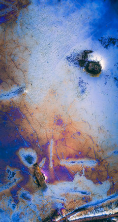 Abstract background of blue and purple oil paint on a metal surface.