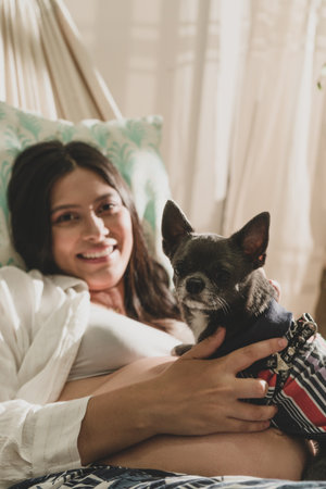 Portrait pregnant woman with dog pet relax lying in a hammock watching the camera