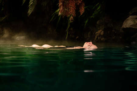 Young woman lying in the water hot spring river termales sanvicente with tropical landscape coffee...