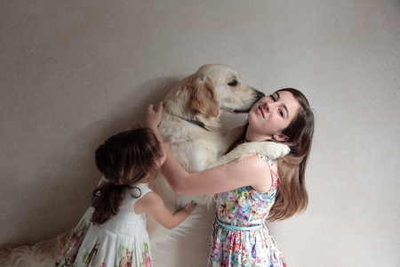 sisters playing with her dog on white backgroundの写真素材