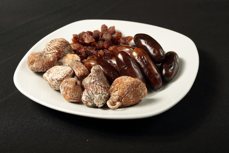 white plate with dried figs, dates and raisinsの写真素材