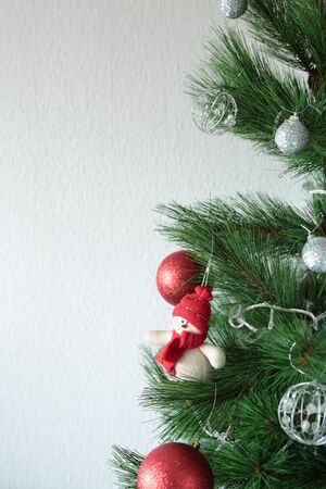 Christmas tree with ornaments on white wall background with space for text
