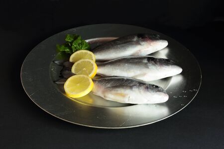 gold raw fish on black background