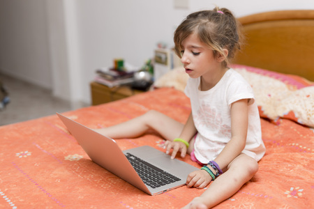 Girl sitting on a bed with your laptop studyingの写真素材