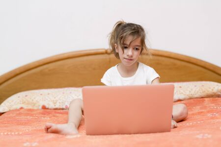 Girl sitting on a bed with your laptop studyingのeditorial素材