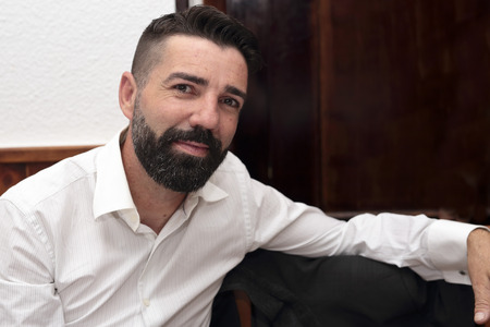 relaxed man with beard sitting on a chairの写真素材