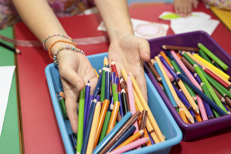 elche, Spain. June 25, 2016: Hands of a girl in a container of crayons.の写真素材