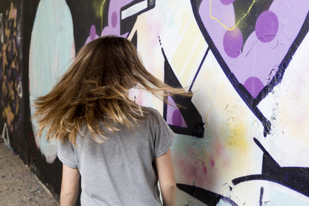 Elche, Spain. October 23, 2016: Teenager going past a graffiti, Which moves you wind your hair. Horizontal image With space for text right.のeditorial素材