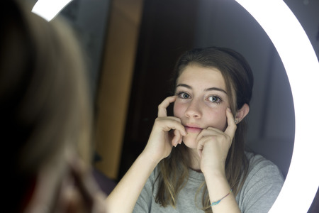 Portrait of teenage looking in a mirror, with the sad and serious face. horizontal shot.