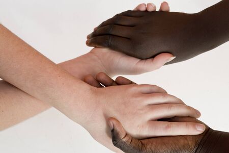 Hands of a girl white and another of color United on a background white. Horizontal shot with natural light.の写真素材