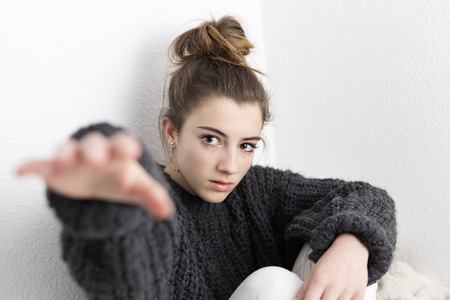Young woman with hand raised on a white background. Horizontal shot with studio light.の写真素材