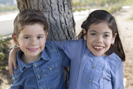 Couple of brothers next to the trunk of a tree. Horizontal shot with natural light.の写真素材