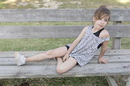 Girl sitting on a wooden bench in a park of Alicante in Spain.の写真素材
