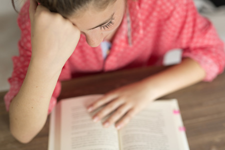 Teen woman reading a book. Horizontal shot with natural light entering through a window.の写真素材