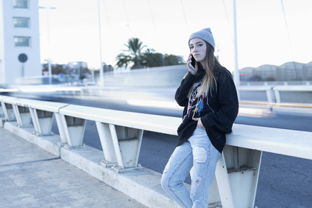 Teenager talking on mobile phone next to a road. Hporizontal shotの写真素材