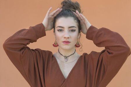18 year old Spanish woman with her hands on her head. Vertical shot with natural light