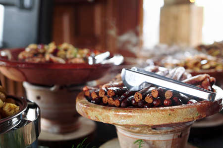 Cooked Belgian food placed in ceramic containers with a fire underneath to keep it warm.の写真素材