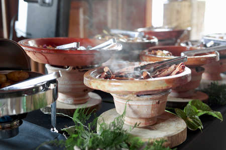 Cooked Belgian food placed in ceramic containers with a fire underneath to keep it warm.の写真素材