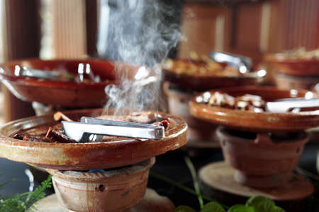 Cooked Belgian food placed in ceramic containers with a fire underneath to keep it warm.の写真素材