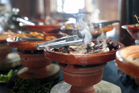Cooked Belgian food placed in ceramic containers with a fire underneath to keep it warm.の写真素材