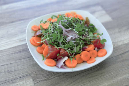 Salad with organic products from the Alicante garden on a white plate on a wooden background.の写真素材