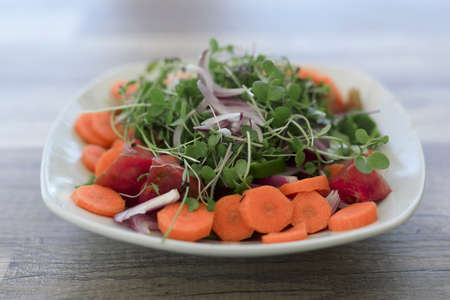 Salad with organic products from the Alicante garden on a white plate on a wooden background.の写真素材