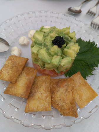Avocado timbale with salmon decorated on a glass plate. Horizontal shot with natural light.の写真素材