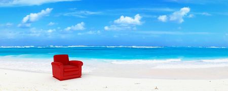 A red club sofa in an idyillic beach of white sand and blue waterの写真素材