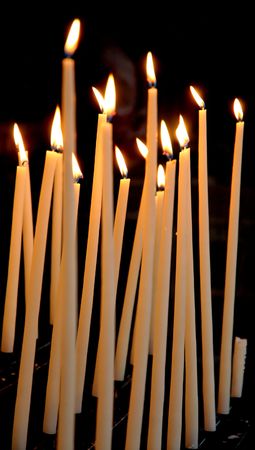 Church candles lit against black backgroundの写真素材