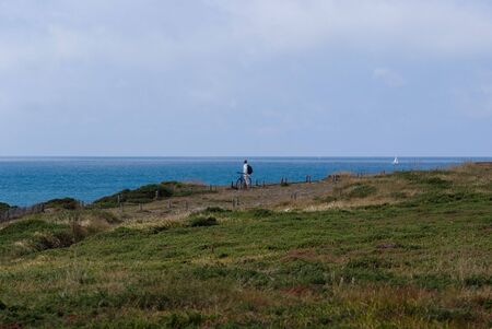 Man with a bicycle looking at the oceanの写真素材