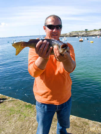 A man holding a sea bass on his hands