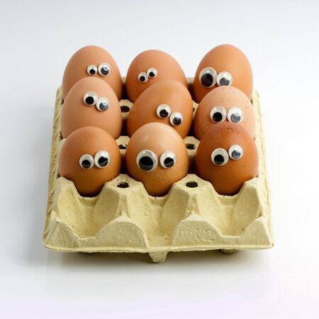 A group of eggs in a box with funny eyes の写真素材
