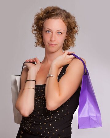 Young blond woman holding two shopping bags against a white backgroundの写真素材