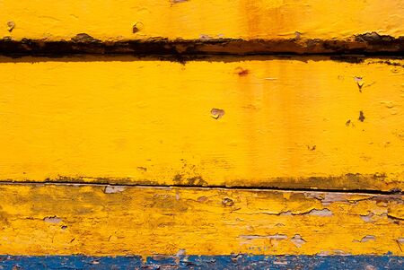Old weather beaten wood painted in yellow and  blue 