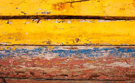 Old weather beaten wood painted in yellow blue and redの写真素材