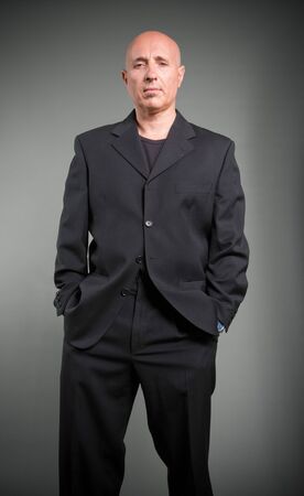 Serious looking bald man in a black costumeの写真素材