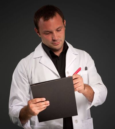 Young man with a medical uniform taking notesの写真素材