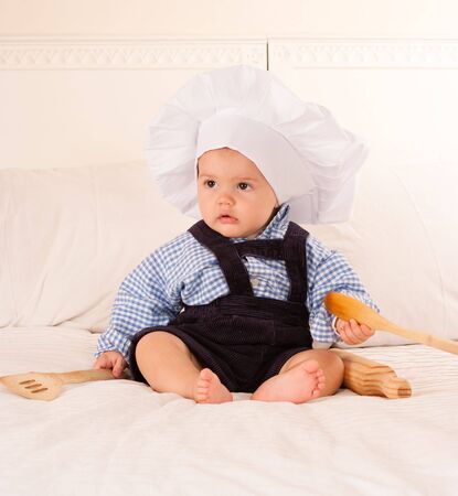 
Cute baby with a cook hat playing with a rolling pin and wooden spoons
の写真素材