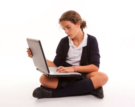 Schoolgirl sitting on the floor working with her laptopの写真素材