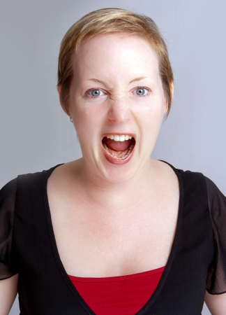 Angry  woman in a shouting fit against a neutral backgroundの写真素材